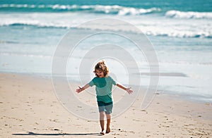 Child boy walk to sea beach, raised hands. Amazed surprised kids emotions.