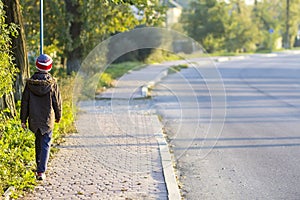 Child boy walking alone on a sidewalk