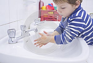 Child boy washing hands at adapted school sink photo