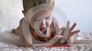 Child boy watch play smartphone on bed at home. distance learning education