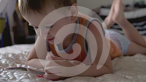 Child boy watch play smartphone on bed at home wearing nappies. distance learning education photo