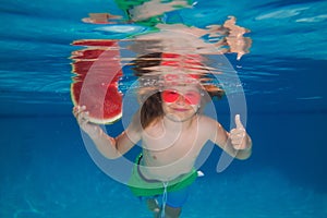 Child boy with watermelon swim under water in sea. Kid swimming in pool underwater. Happy boy swims in sea underwater