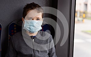 Child boy wearing medical protective mask in public transport bus.