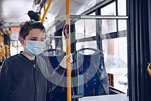 Child boy wearing medical protective mask in public transport bus.