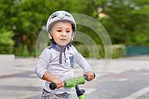 Child boy in white helmet riding on his first bike with a helmet. Bike without pedals.