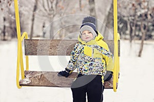 The child. boy in winter clothes riding on a swing, emotion, laughing, winter, snow