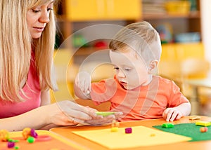 Child boy and woman play colorful clay toy at nursery or kindergarten
