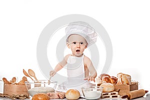 Child with bread on bakery-like background wearing cook-hat. Little baker