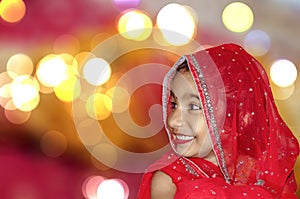 Child bride in red saree and bokeh light in backgr