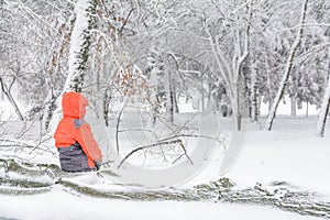 Child and broke down tree of snow. Child sitting over the trunk