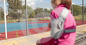 A child with a broken arm outdoors near a playground fence.