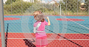 A child with a broken arm outdoors near a playground fence.