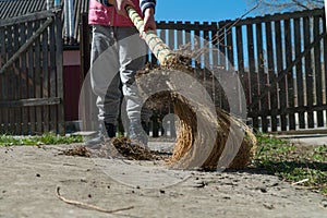 Child with a broom removes garbage in the yard