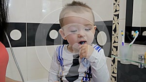 A child is brushing his teeth in front of a mirror.