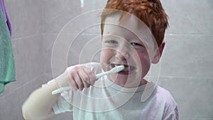 Child brushing teeth in front of mirror in bathroom in the morning