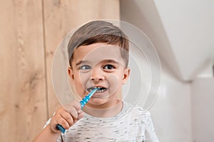Child brushing teeth. Kids tooth brush and paste. Little funny baby boy brushing his teeth in modern bathroom on sunny