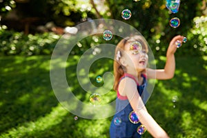 Child, bubbles and garden grass for playing in summer sunshine in backyard for holiday, carefree or happy. Kid, girl and