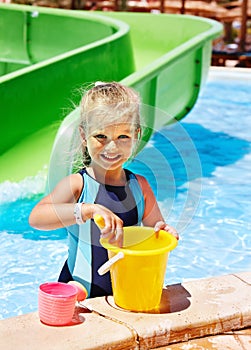 Child with bucket in swimming pool.