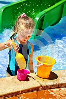 Child with bucket in swimming pool.