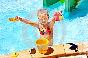 Child with bucket in swimming pool.