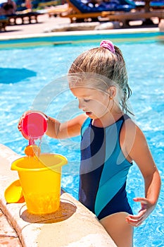 Child with bucket in swimming pool