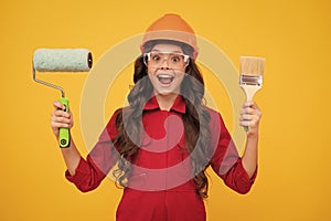 Child builder in hard hat helmet. Teenage girl painter with painting brush tool or paint roller. Teenager worker
