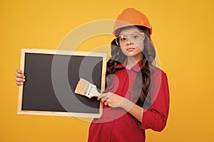 Child builder in helmet. Teenage girl painter with painting brush tool or paint roller. Child on repairing work 