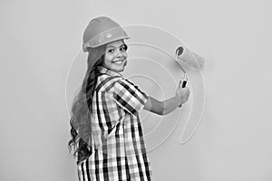 Child builder in helmet. Teenage girl painter with painting brush tool or paint roller. Child on repairing work 