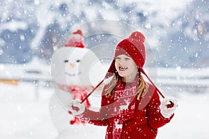 Child building snowman. Kids build snow man