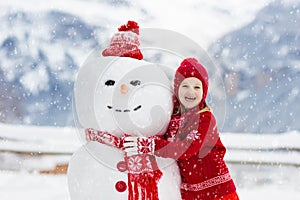 Child building snowman. Kids build snow man