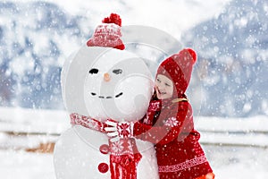 Child building snowman. Kids build snow man