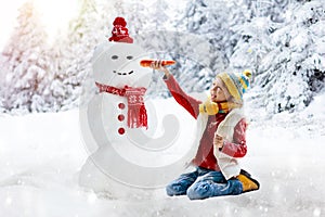 Child building snowman. Kids build snow man