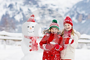 Child building snowman. Kids build snow man