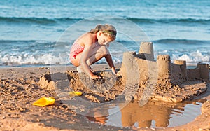 Child builds sandcastle on the beach