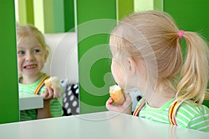 Child with bun peers into mirror