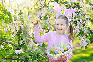 Child with bunny ears on garden Easter egg hunt