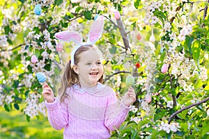Child with bunny ears on garden Easter egg hunt