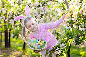 Child with bunny ears on garden Easter egg hunt