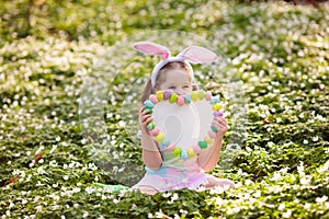 Child with bunny ears on garden Easter egg hunt