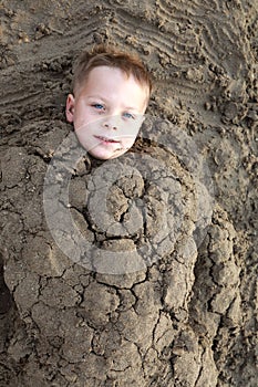 Child buried in sand on beach
