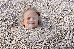 Child buried under the stones, only head can be seen