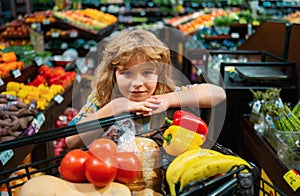 Child buying fruit in supermarket. Kid buy fresh vegetable in grocery store. Kids in shop, healthy food. Shopping cart