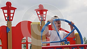 Child captain at helm boat playground wooden ship in park game pirate. Little captain wheel steering boat rudder ship