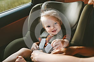 Child in a car girl in safety seat and mother fastens belt family lifestyle vacation