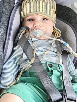 Child in a car seat with baby`s dummy