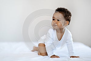 Child Care. Black Baby Boy Or Girl Crawling On Bed At Home