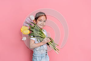 A child carries a bouquet of tulips on his shoulder against a pink background