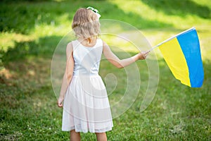 Child carries fluttering blue and yellow flag of Ukraine in field. Ukraine`s Independence Day. Flag Day. Constitution day. Girl i