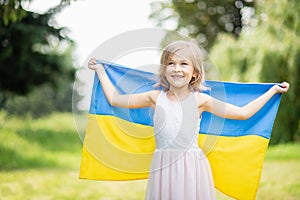 Child carries fluttering blue and yellow flag of Ukraine in field. Ukraine`s Independence Day. Flag Day. Constitution day. Girl i