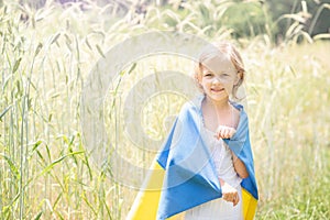 Child carries fluttering blue and yellow flag of Ukraine in wheat field. Ukraine& x27;s Independence Day. Flag Day